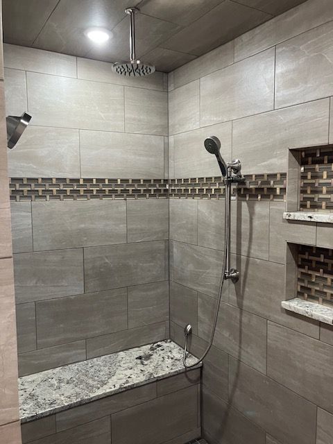 Tiled shower with a bench, rain showerhead, hand-held shower, and built-in shelves.