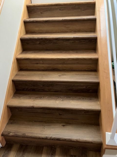 Wooden staircase with brown treads and light wood trim, viewed from below.