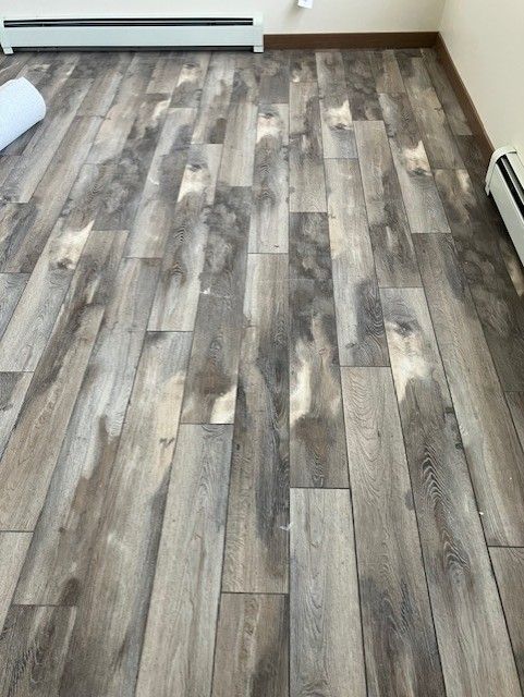 Grey and brown wood-look flooring, installed with varying shades and textures, fills a room.
