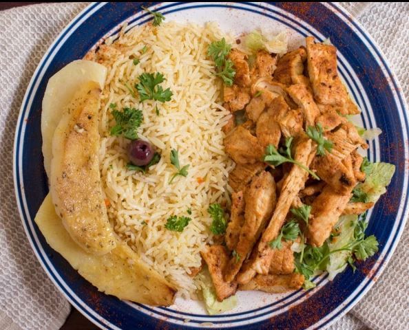 A plate of food with rice and chicken on a table.