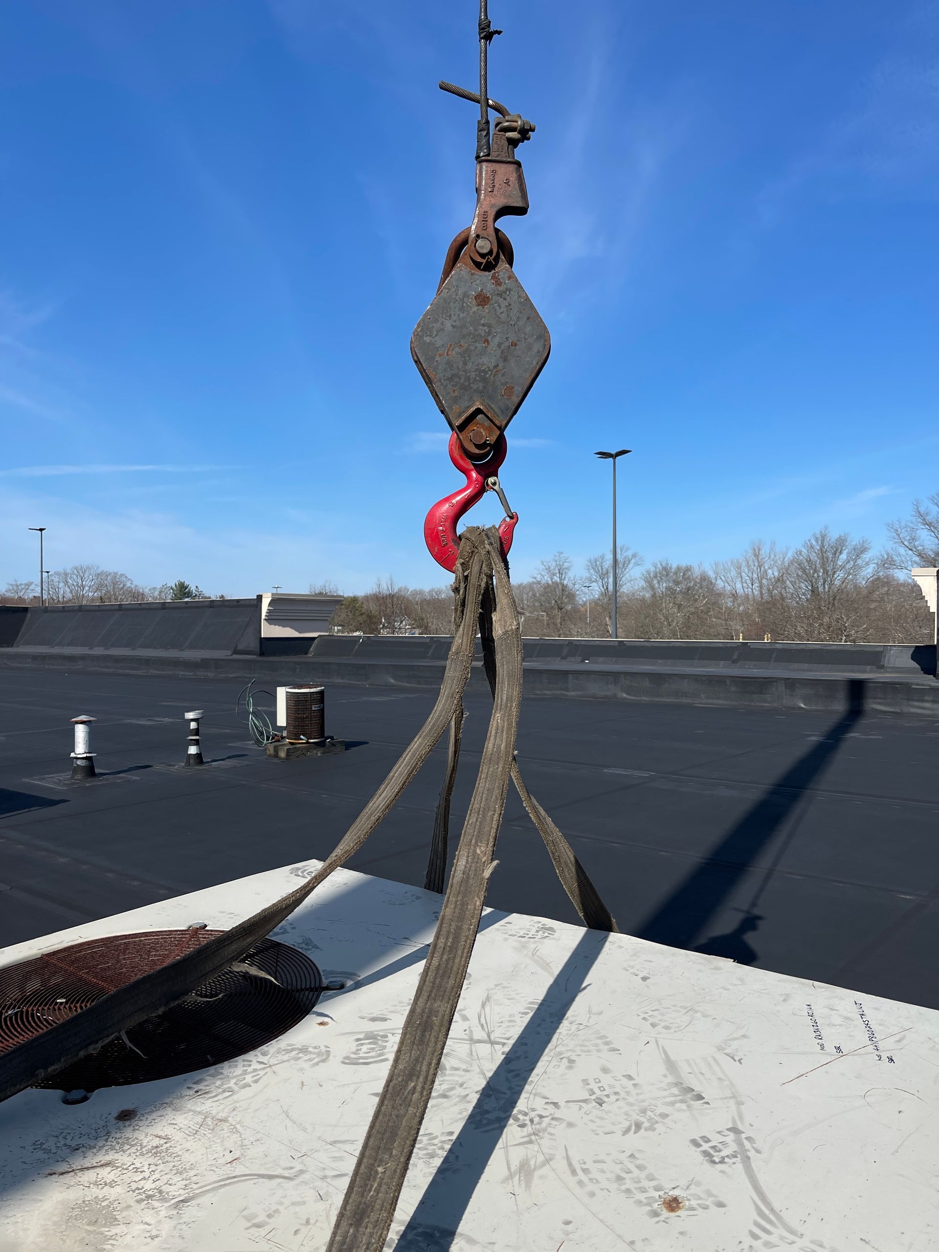 A crane hook with a red hook is attached to a rope
