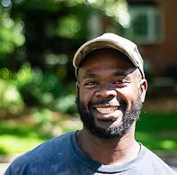 A man with a beard and hat is smiling for the camera.