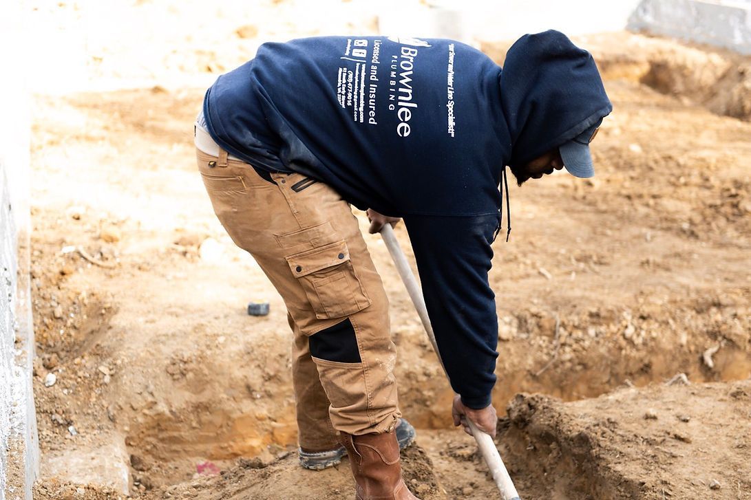 A man in a blue hoodie is digging in the dirt with a shovel.