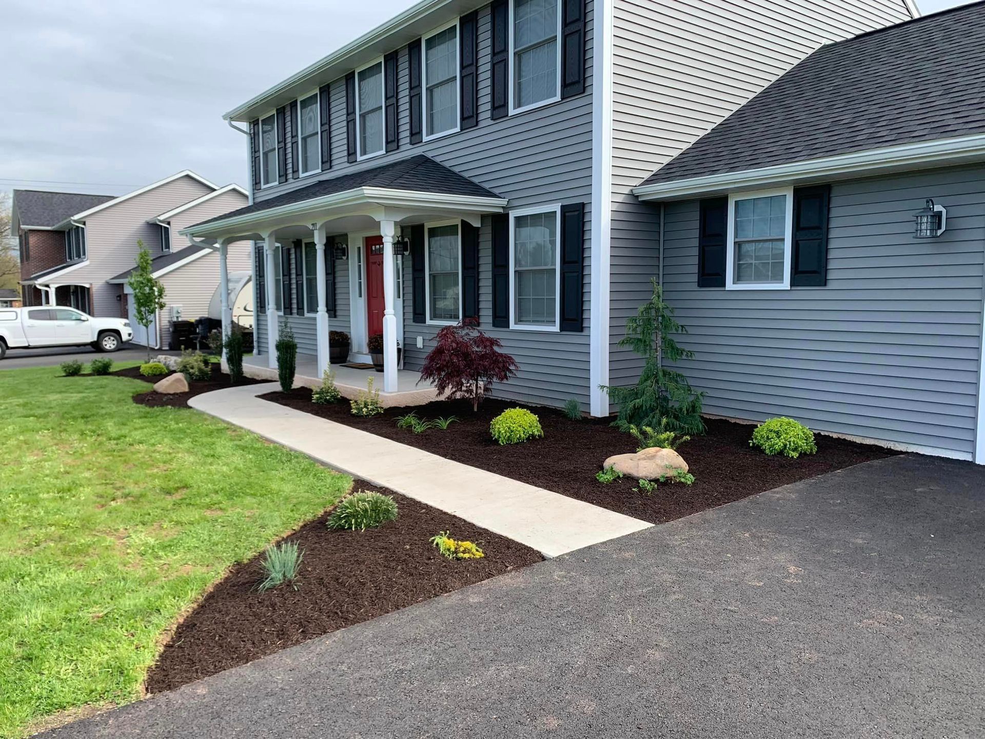 A house with a walkway leading to the front door and a car parked in front of it.