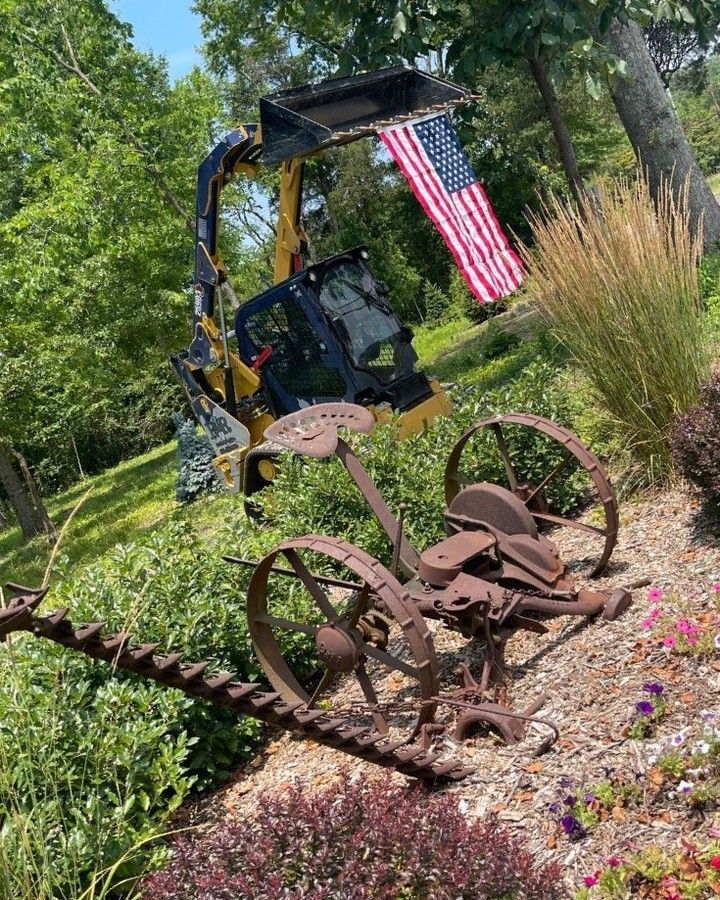 A tractor with an american flag on top of it is parked in a garden.