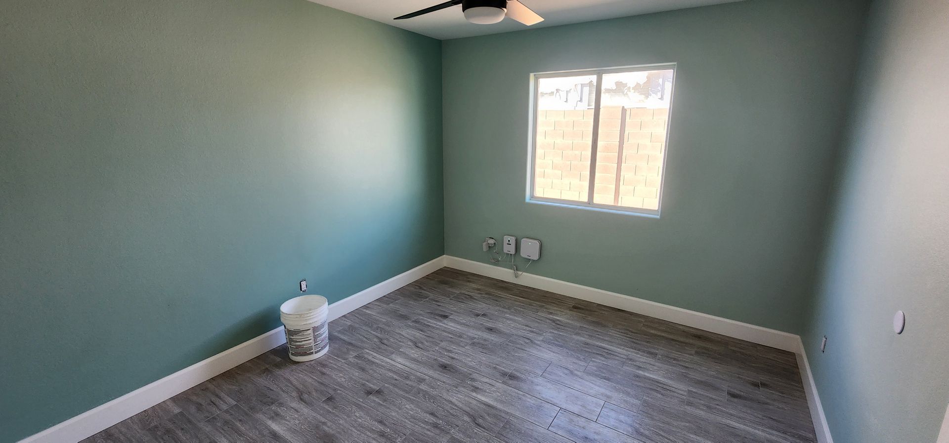 Empty painted bedroom with green walls, gray carpet, and a small window.