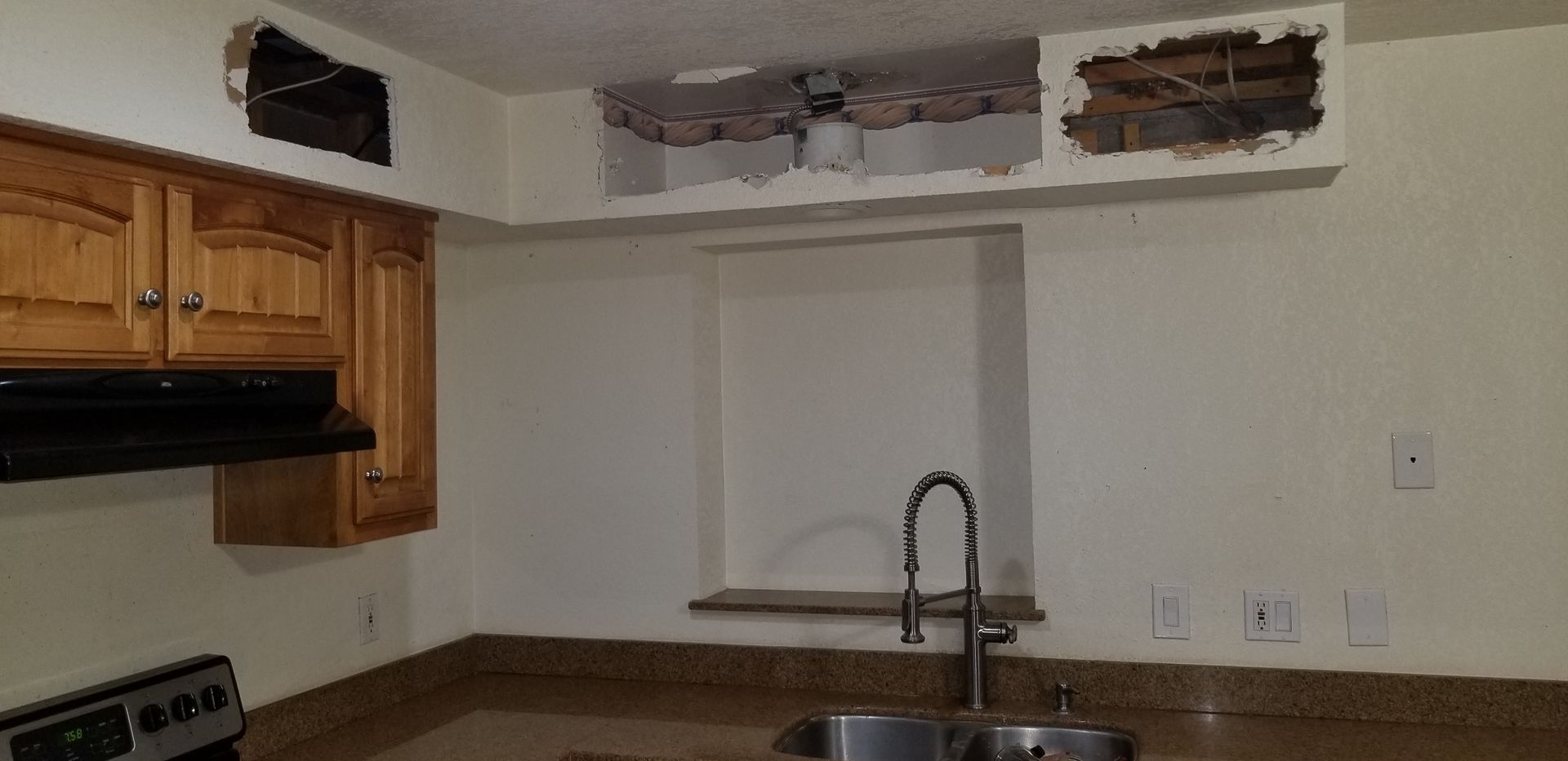 Small kitchen with wood cabinets, white walls, and a sink under a window opening.