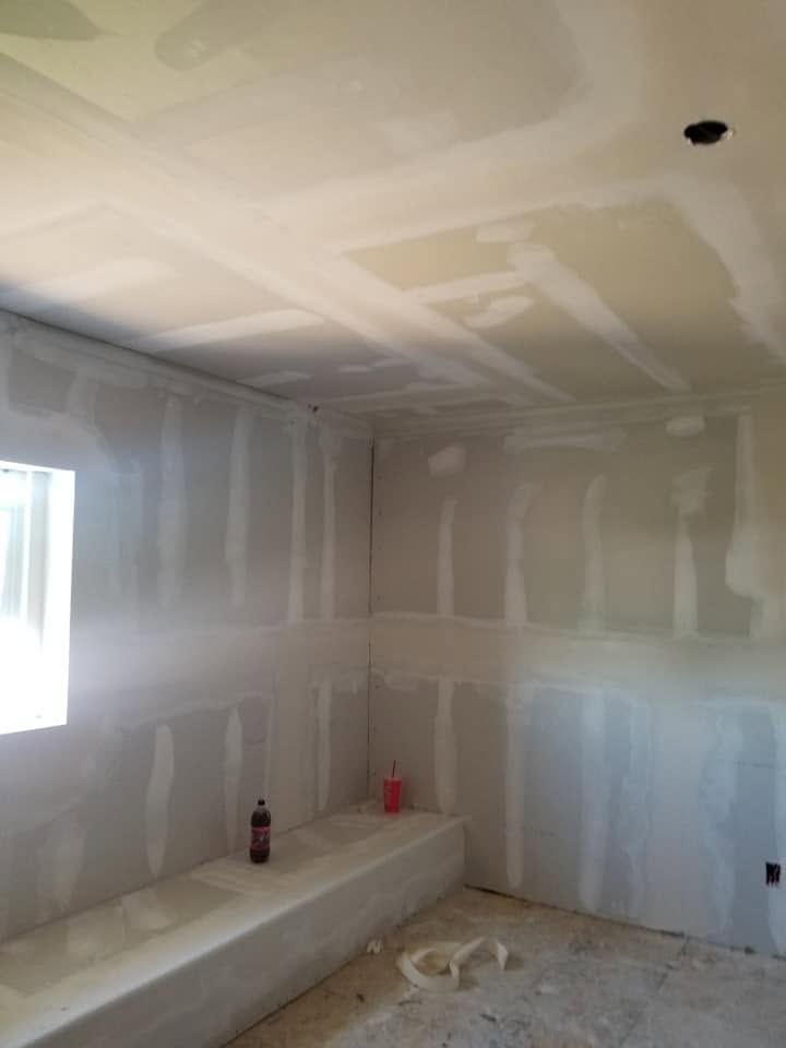 Unfinished room with taped drywall, a built-in bench, and a small window letting in light.