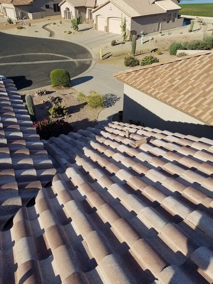 Rooftop view of tan tile roofs, a curved street, and beige houses in a sunny suburban neighborhood