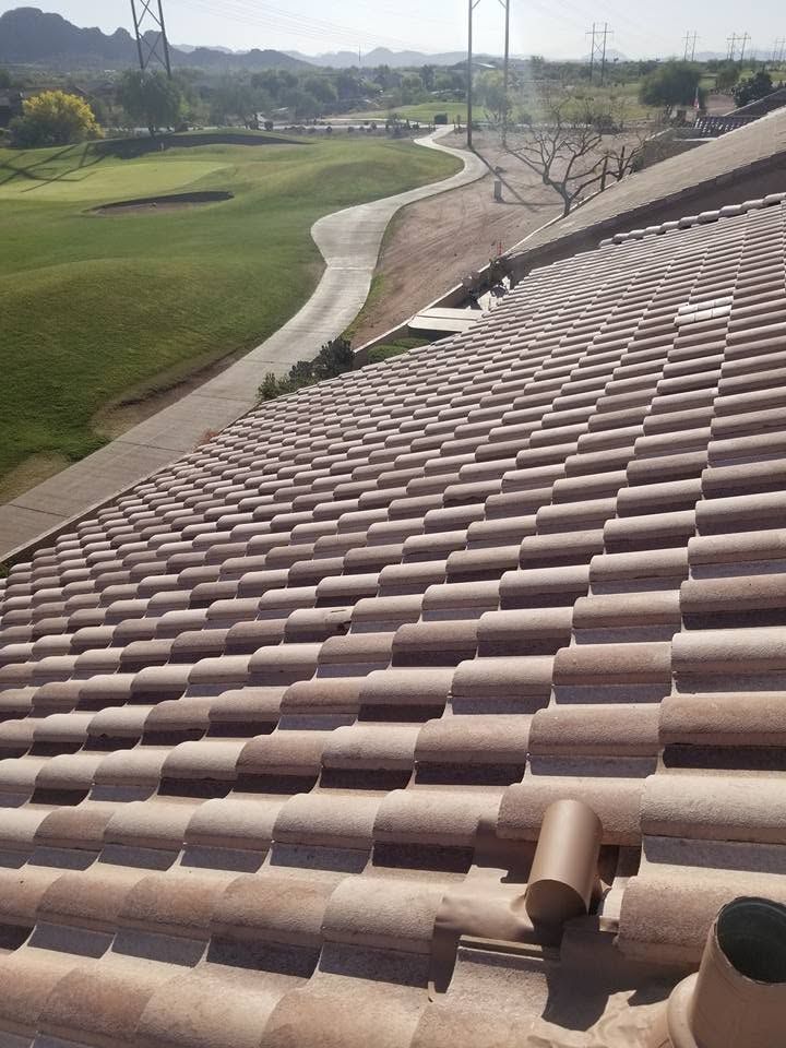 Roof with brown tiles overlooking a golf course and winding path on a sunny day