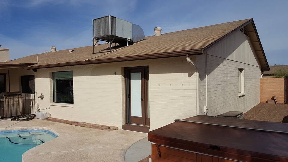 Backyard patio beside a beige house with a pool and rooftop HVAC unit