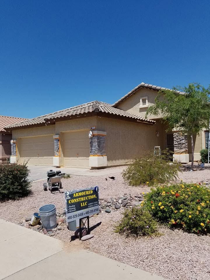 Single-story stucco house with a for-sale sign in a desert-style front yard under a blue sky