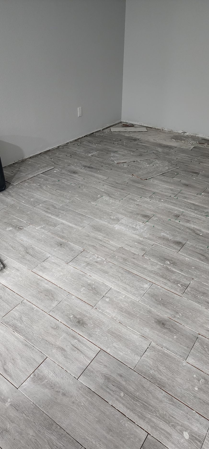 Empty room corner with gray walls and light wood flooring.