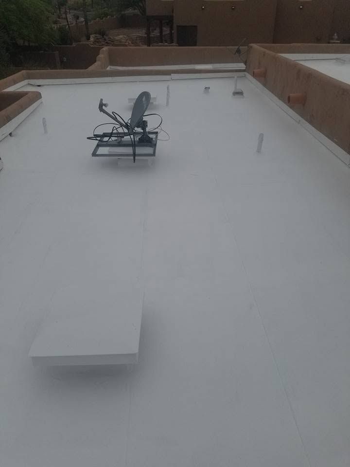 White rooftop with a small chair set and a rectangular vent in the foreground