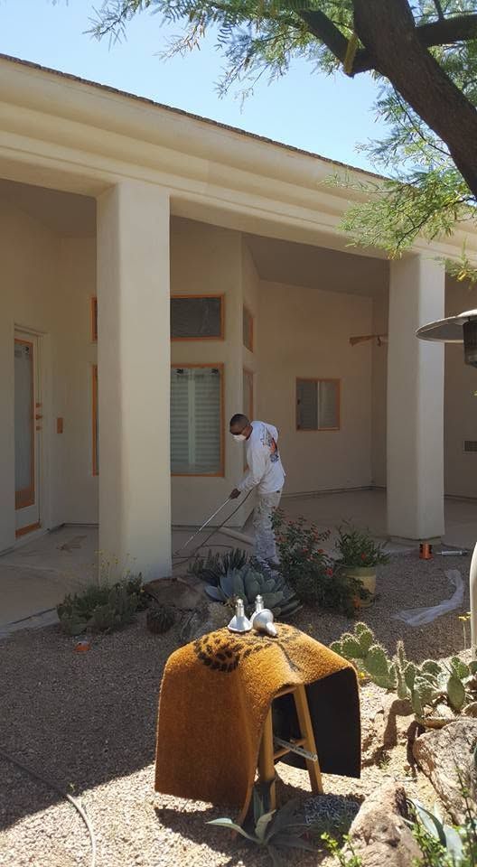 Person walking outside a beige building with tall columns, near a small pumpkin-shaped display in the foreground