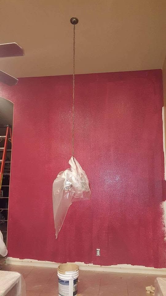 Magenta painted wall under repair, with peeling paint, hanging plastic, and a ladder at left.