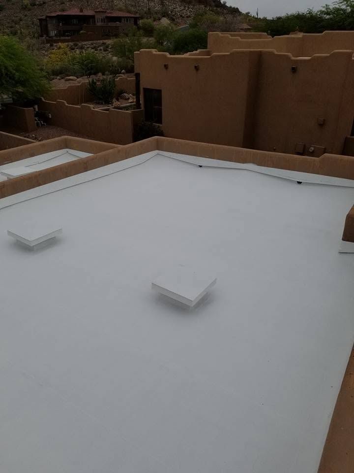 White rooftop with two small vents, overlooking tan stucco buildings and desert landscaping