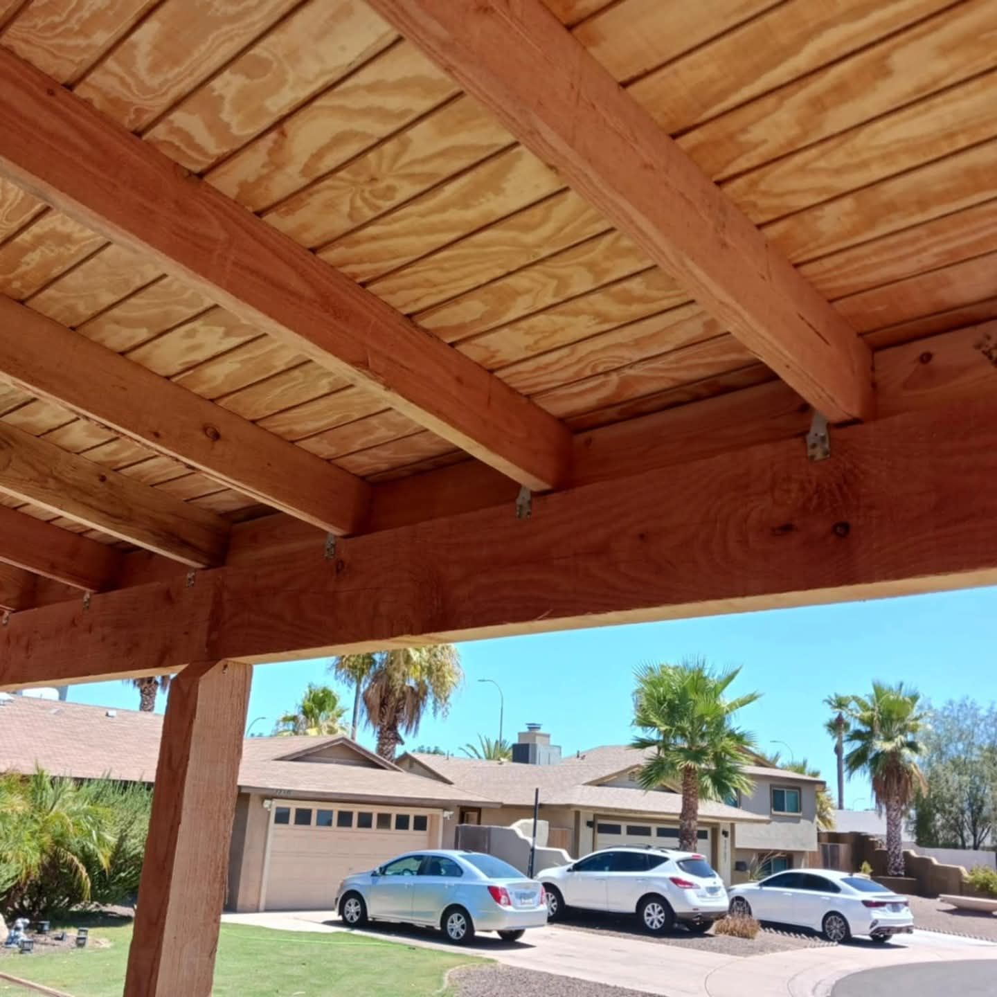 Covered patio beams overlooking parked cars and stucco houses on a sunny street