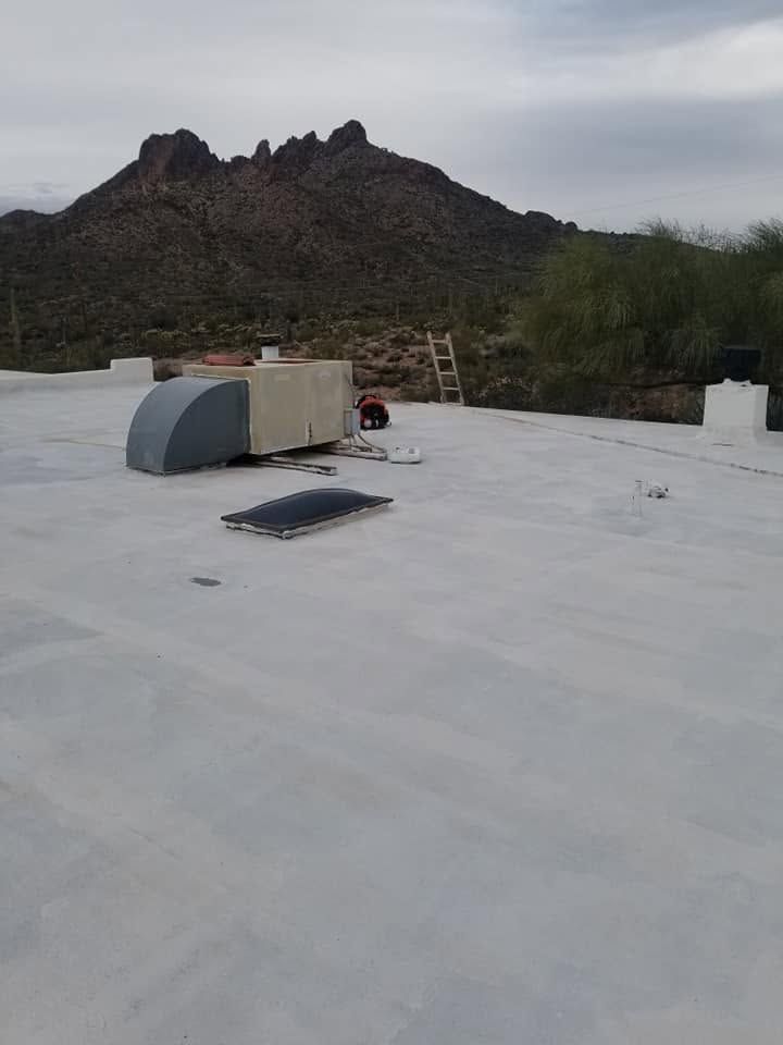 Flat white rooftop with HVAC units, a ladder, and desert mountains in the background