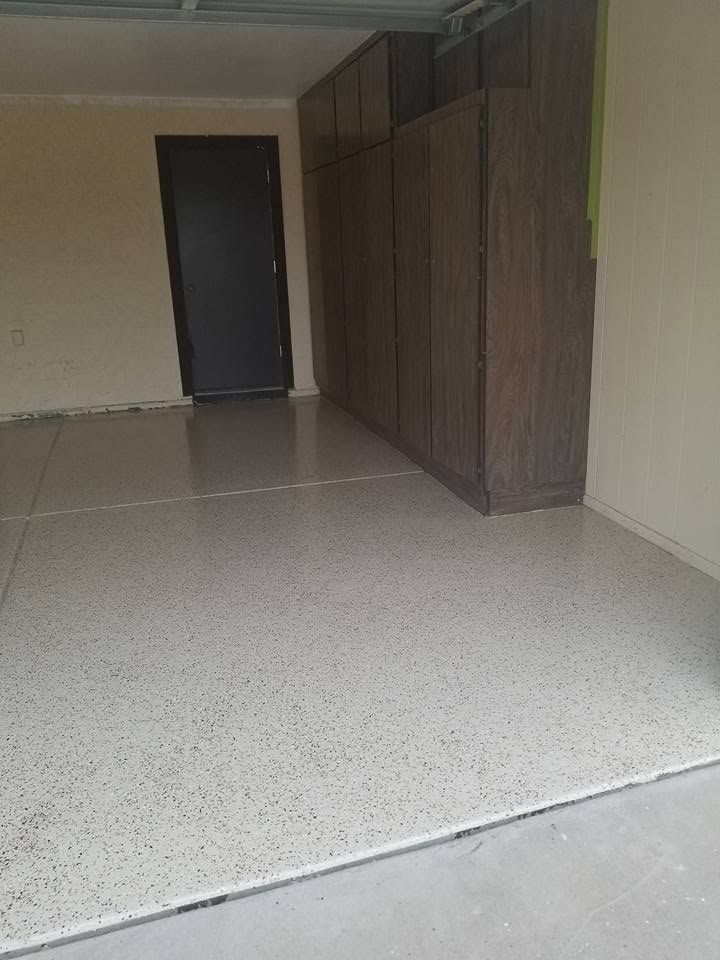 Empty indoor hallway with terrazzo floor, beige walls, wood-paneled storage units, and a dark door at the end