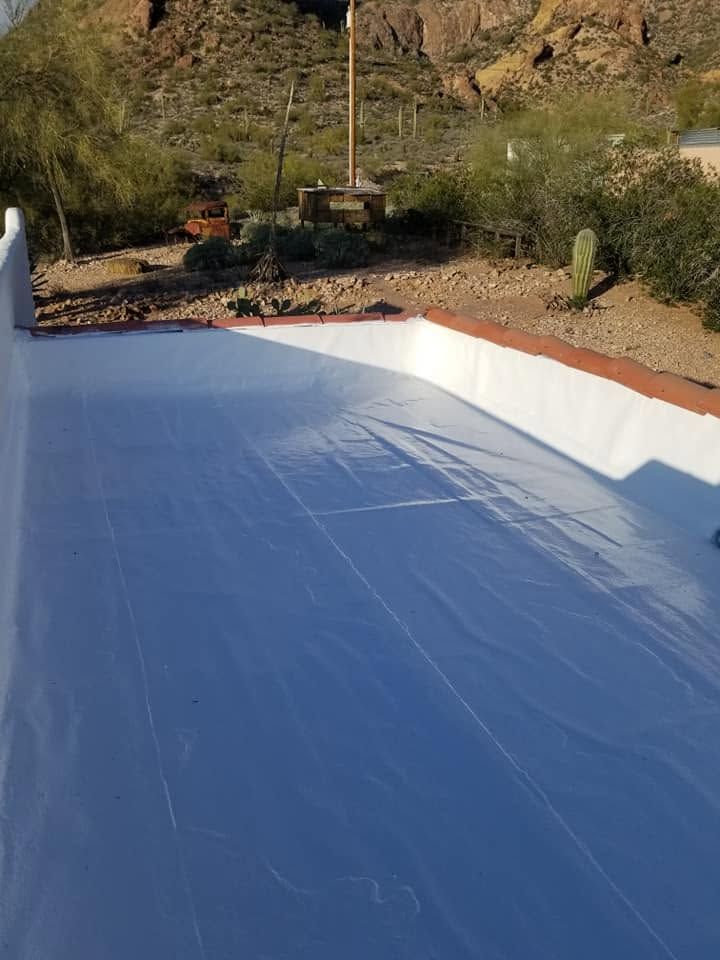 Blue pool liner in a partially filled outdoor pool with desert shrubs and hills in the background