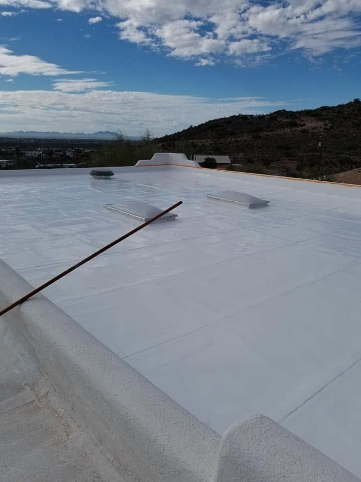 White rooftop with a long cable, blue sky, and hills in the distance.