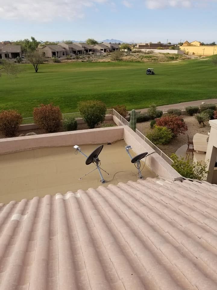Patio overlooking a green golf course with beige rooftops and two satellite dishes in the foreground