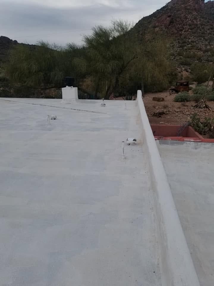 White rooftop terrace with low walls, overlooking trees and a rocky hillside at dusk