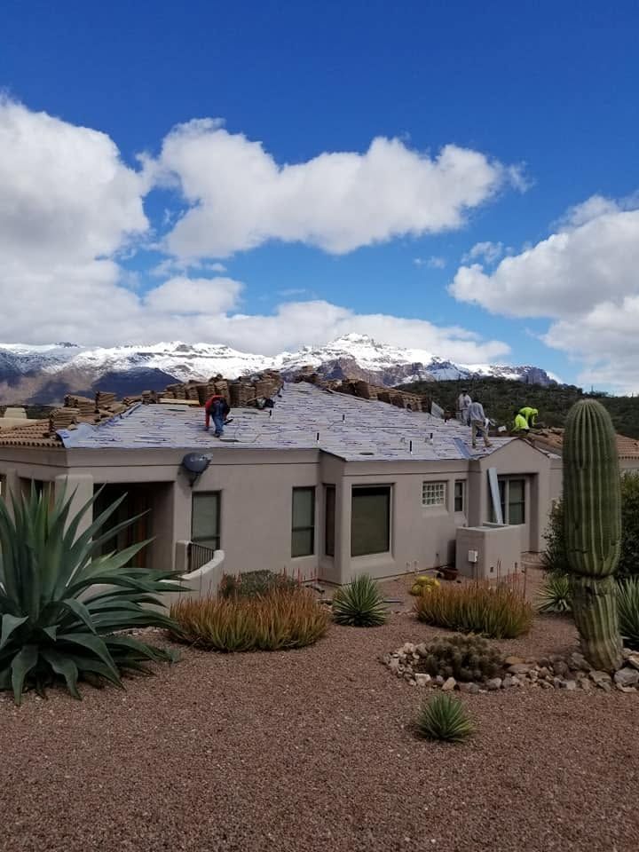 Desert home with snowy mountains, blue sky, and cactus in the front yard
