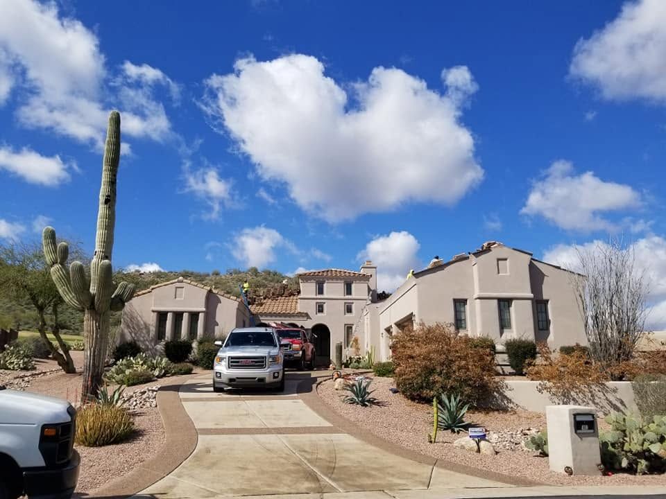 Desert home driveway with parked SUV, cacti, and blue sky with clouds
