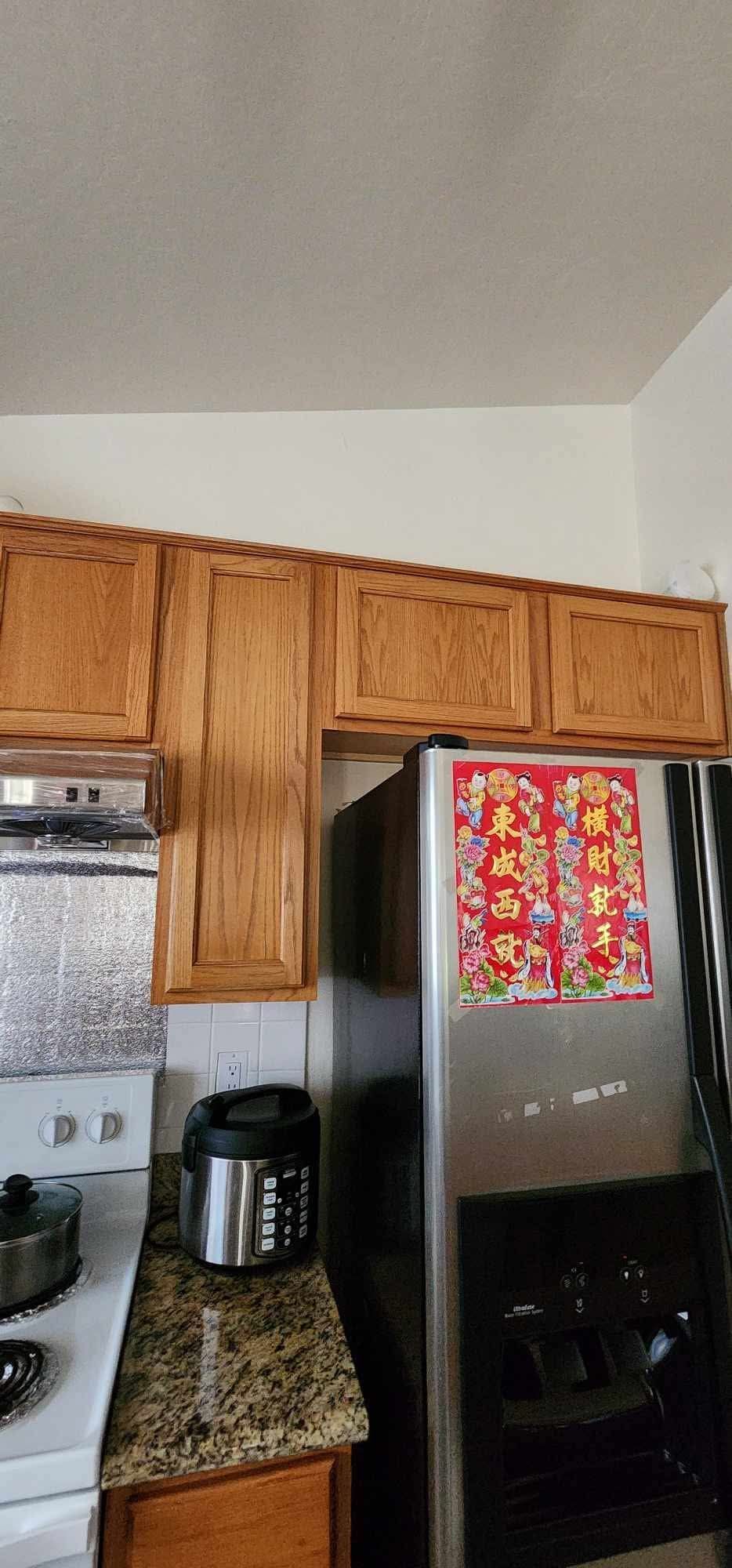 Kitchen corner with wooden cabinets, granite counter, and stainless steel refrigerator with colorful magnets.