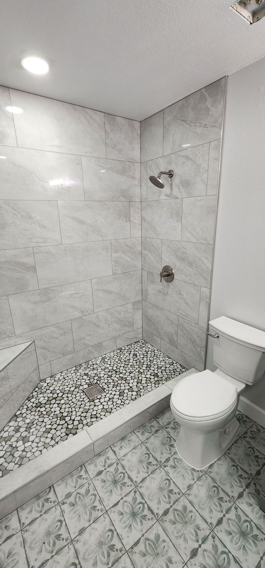 Small tiled bathroom with a walk-in shower and a white toilet.