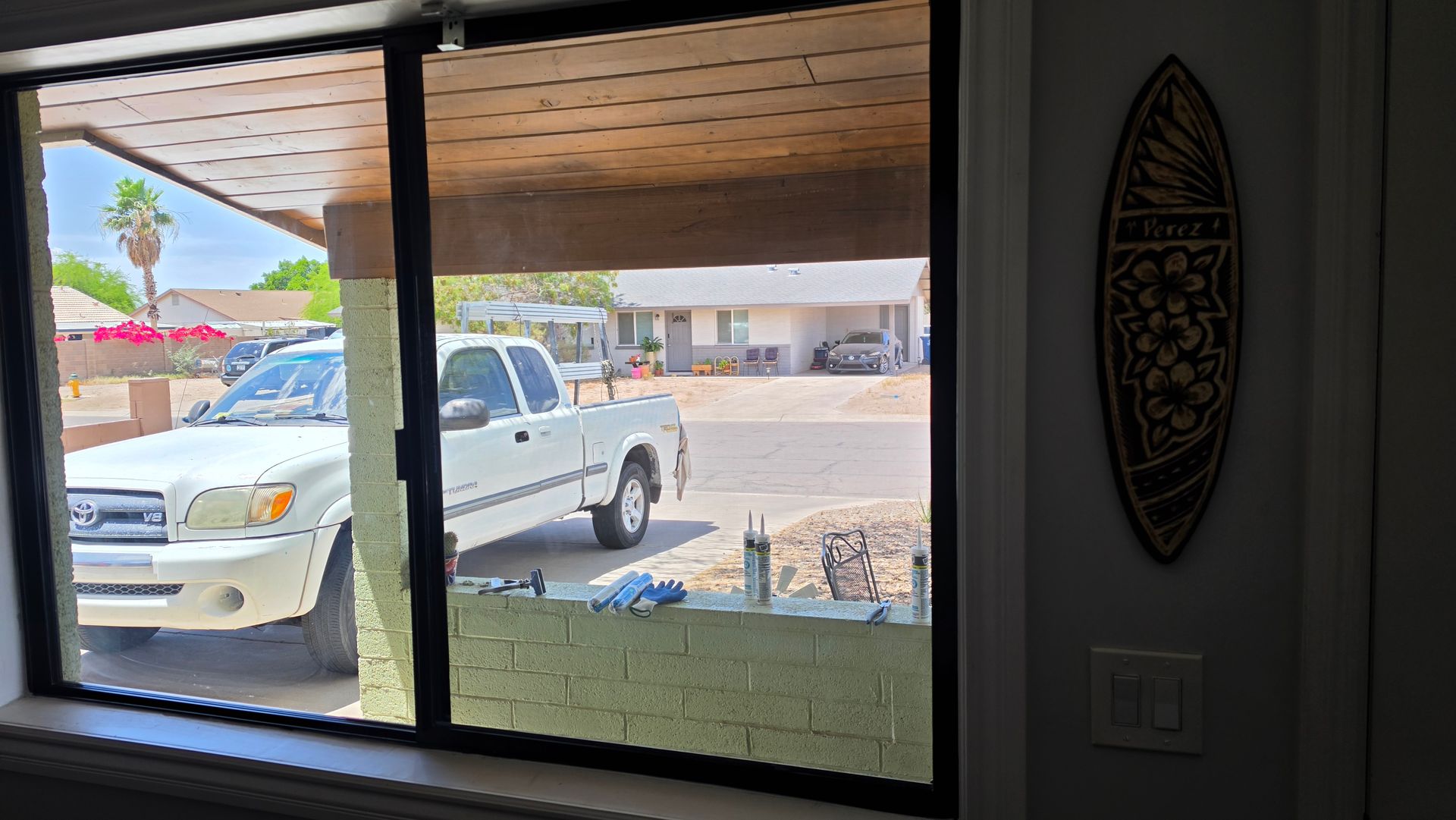 View through a window of a white pickup truck parked outside a house with a desert landscape.