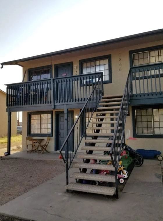 Apartment building exterior with exterior stairs, second-floor balconies, and items stored under the stairs