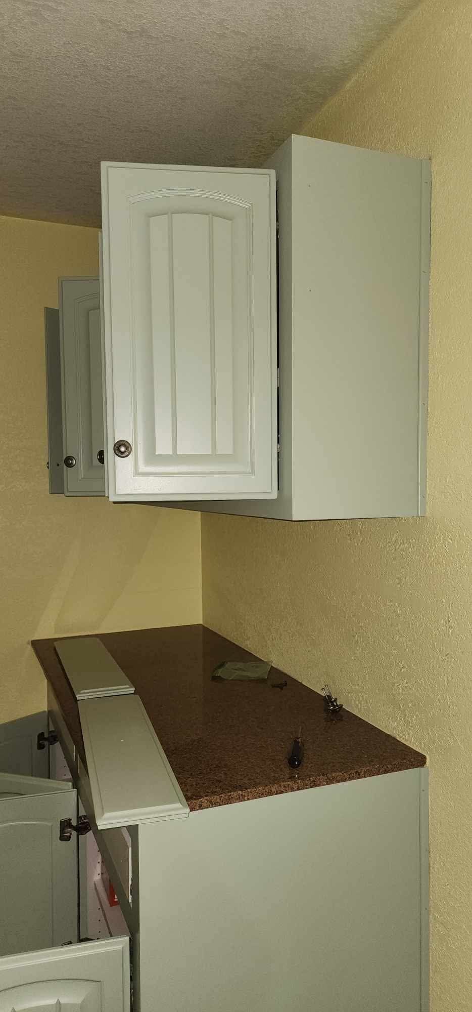 Small kitchen area with white cabinets above a brown countertop and a white appliance below.