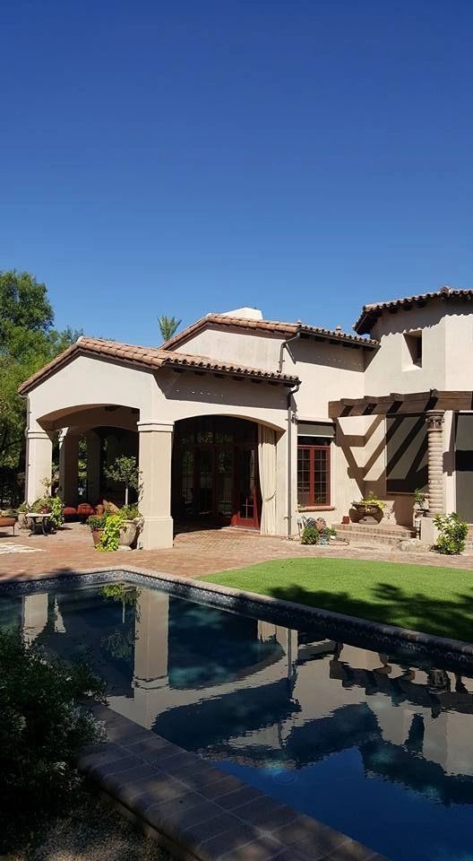 Sunny backyard with a Mediterranean-style house, pool, and clear blue sky