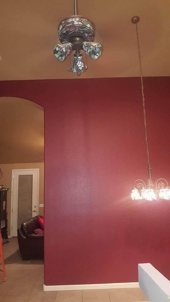 Empty room with burgundy walls, white trim, chandelier lights, and a doorway to another room