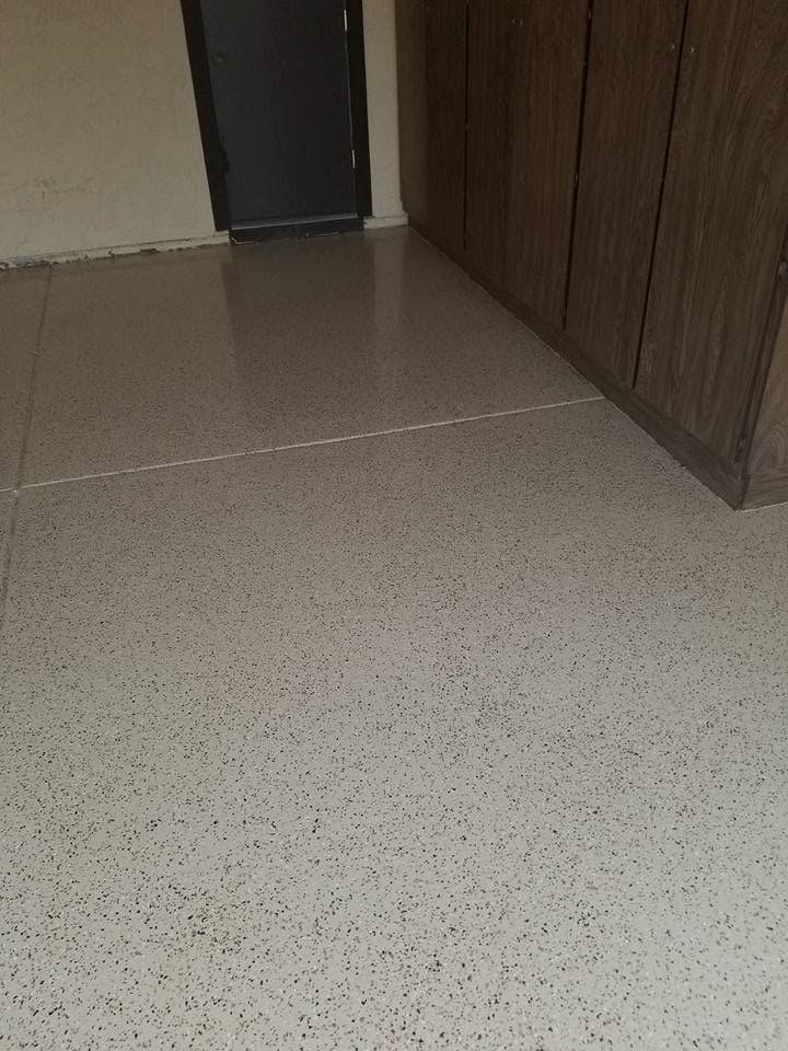 Empty tiled hallway with a dark door and brown cabinets along the wall