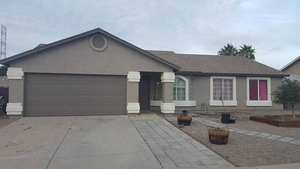 Single-story suburban house with a two-car garage, concrete driveway, and desert landscaping.