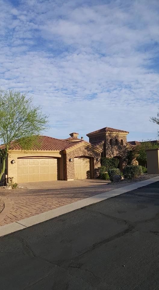 Desert-style stucco house with a garage, stone accents, and a clear blue sky at sunset