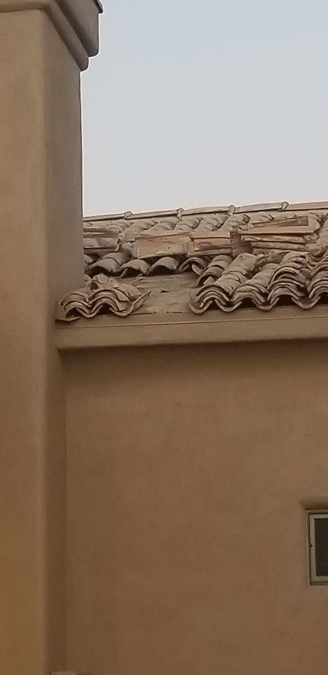 Tan stucco building with terracotta roof tiles against a pale sky