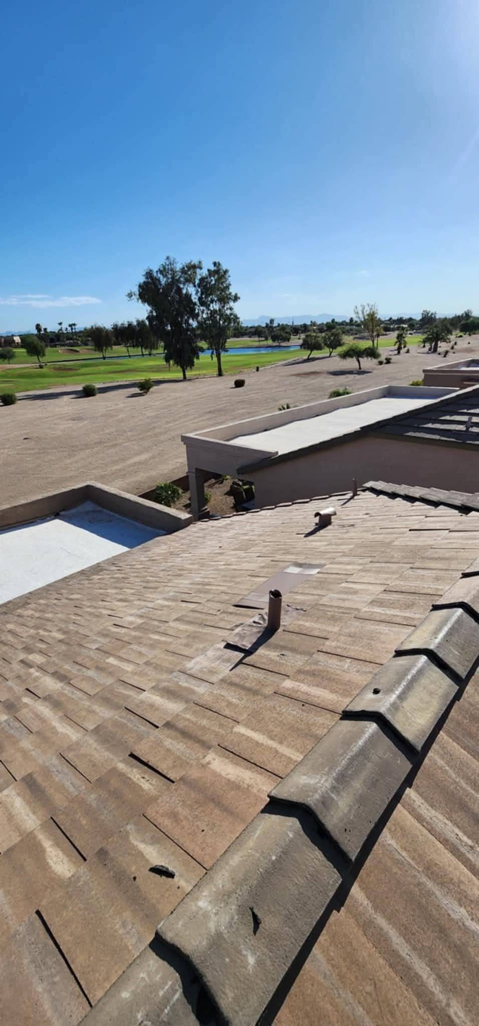 Rooftop under clear blue sky with brick shingles and a distant green landscape