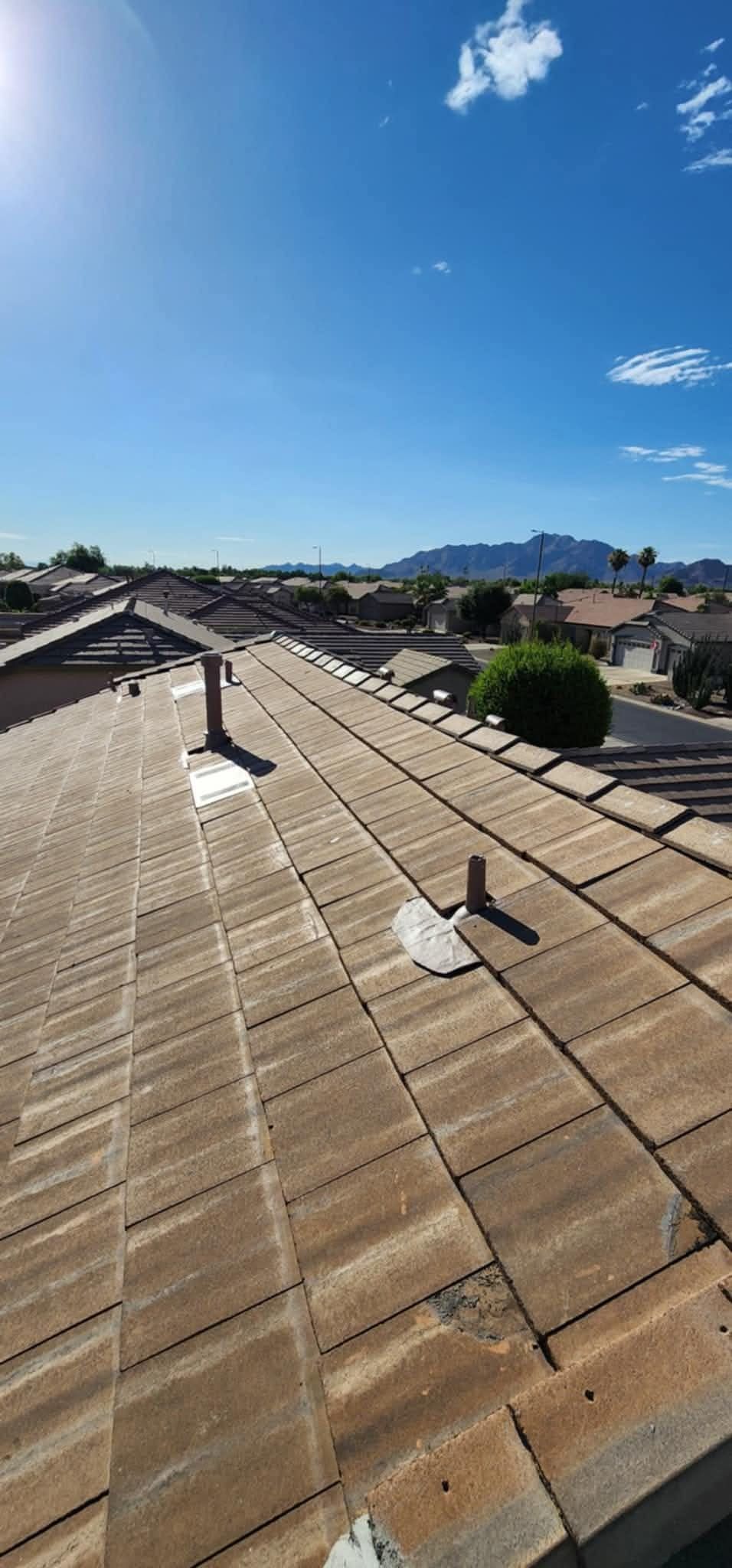 Tiled rooftops under a clear blue sky with distant mountains and a few scattered clouds