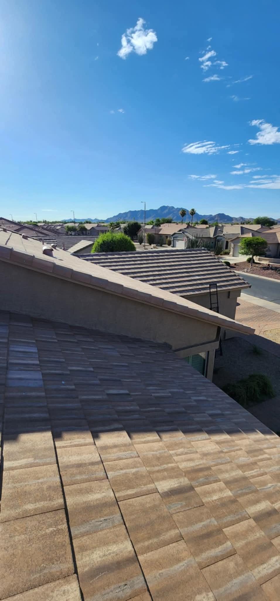 Rooftops of suburban homes under a bright blue sky with distant mountains.