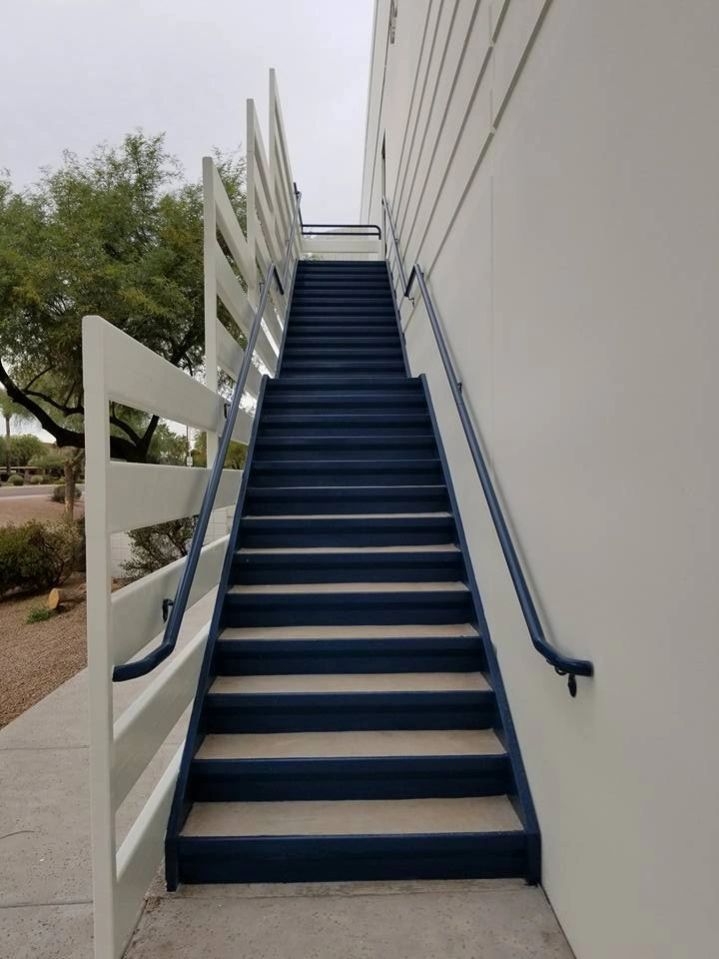 Outdoor staircase with blue steps and white railings beside a white building