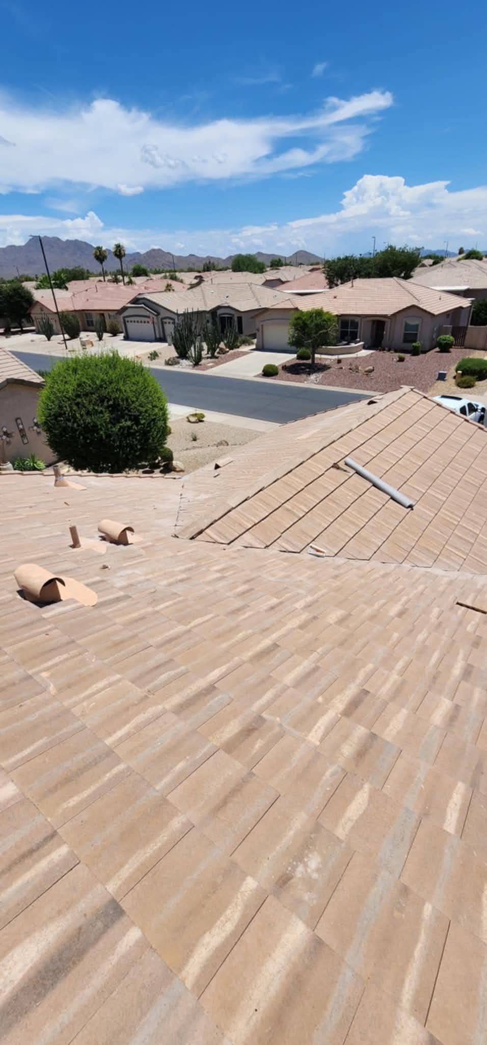 View from a tiled rooftop over suburban houses and mountains under a blue sky