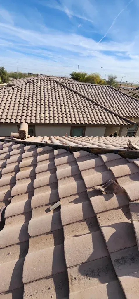 Tile rooftops under a clear blue sky, with a close-up roof in the foreground
