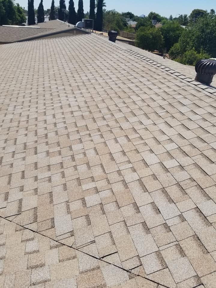 Rooftop with light tan brick pavers and small vents along the edge under a clear sky