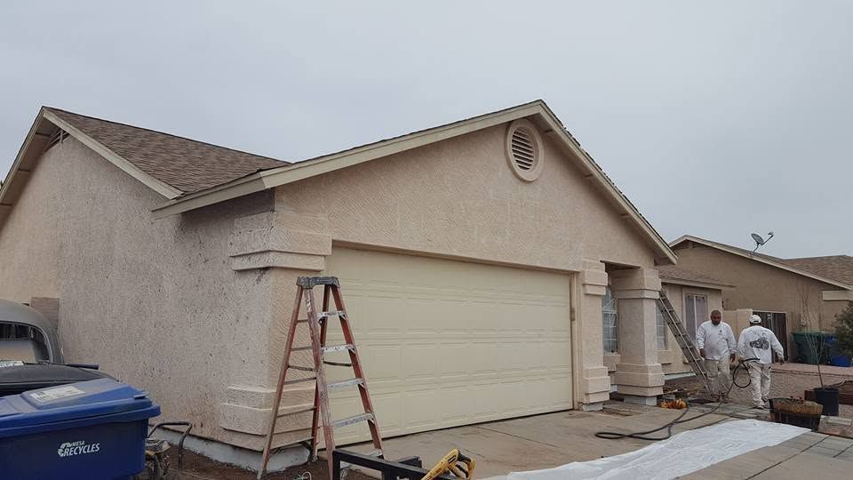 House exterior under repair with ladder, workers, and construction materials on the driveway
