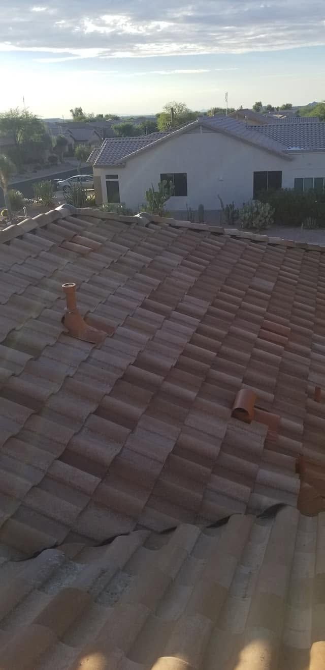 Rooftop with red tiles overlooking a suburban neighborhood at sunset.